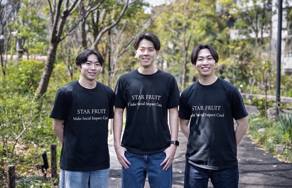 STARFRUIT のメンバー3名。「STAR FRUIT / Make Social Impact Cool」のロゴ入りTシャツを着て緑の中に立つ写真